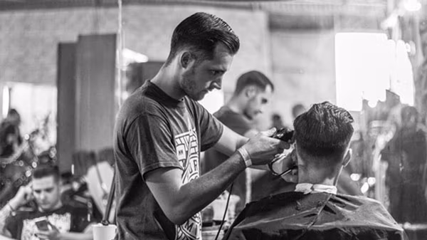 Fryzjer strzyże mężczyznę w salonie fryzjerskim u barbera.